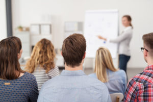 42555956 - rear view of young office workers in casual outfits listening to a top manager explaining something using illustrations.